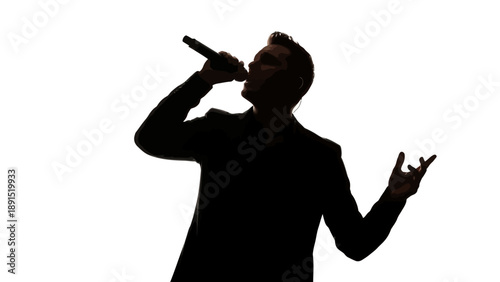 Silhouette of a man singing into a microphone on stage.