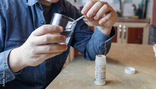 Wallpaper Mural A man in the kitchen tests tap water quality with a test strip. Home testing for drinking water safety, pH, chlorine, and chemical contaminants. Torontodigital.ca