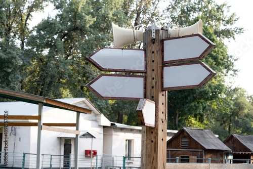 Foto Blank wooden directional arrow signpost with speakers mounted on top in public park outdoor