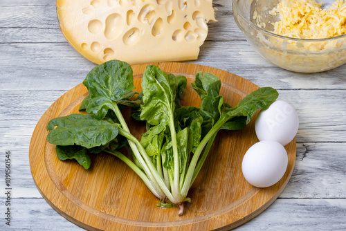 A plate with spinach on a wooden table. Spinach leaves in a bowl.