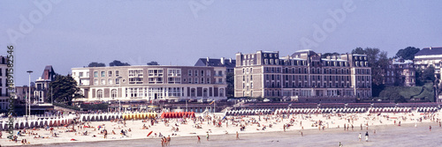 Принти на полотні Dinard, Ille-et-Vilaine, France, August 1973: crowded summer beach with bathers and striped cabins along the seafront