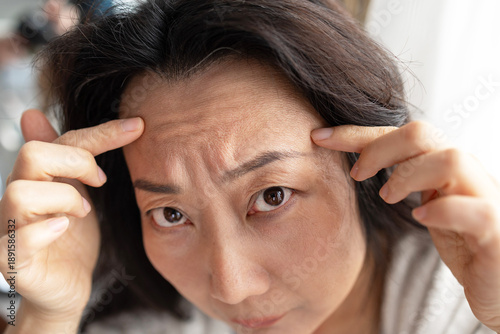 Foto closeup portrait of Asian middle age woman showing her skin closeup showing wrinkles in her forehead