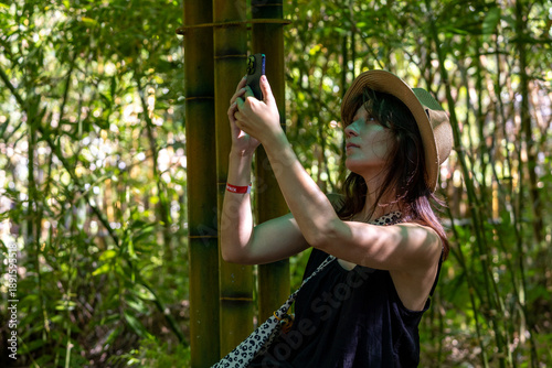 Bilde på lerret Exploring nature’s beauty: a young woman in a straw hat captures the mesmerizing