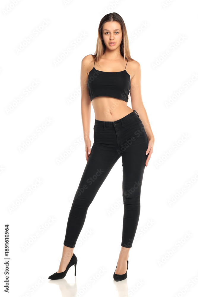 Fototapeta premium Studio shot of a natural woman with long dark hair wearing a black top, black pants and high heels, full body, on a white background