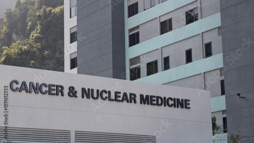 Fotografie Exterior view of a modern medical facility featuring a prominent sign for a Cancer & Nuclear Medicine department, indicating specialized healthcare services for oncology and diagnostics