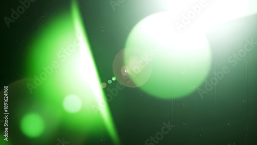 Green light beams and lens flares on a dark background with bokeh effect