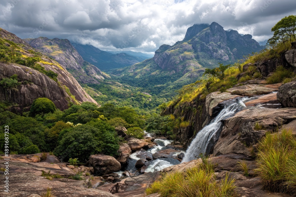 Obraz premium Scenic vista of waterfall cascading into a lush valley, surrounded by towering mountains