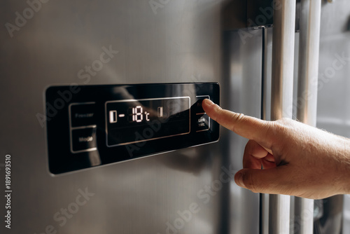 Fotografía Hand adjusting temperature settings on modern refrigerator control panel, digita