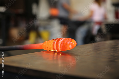 Foto Glowing molten glass on blowpipe being shaped on tabletop