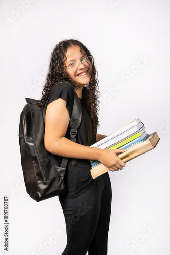 Brazilian teenager, a Brazilian teenager holding many heavy books and notebooks in her hands, white background, selective focus.
