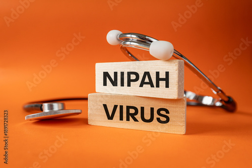 Nipah virus from the Henipavirus genus. Concept of health. Infectious disease, often fatal. A medical stethoscope, written on white blocks, NIPAH VIRUS. Close up. orange background