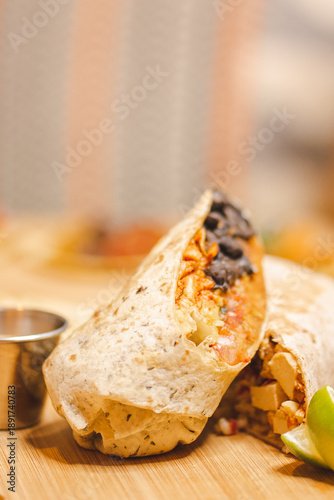 Cut burrito with chicken, rice and black beans on wooden board