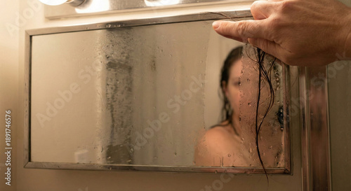 Hand wiping foggy bathroom mirror after shower