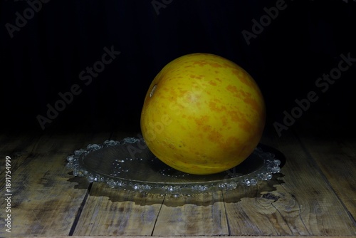 Image of a whole melon on a plate on a dark background.