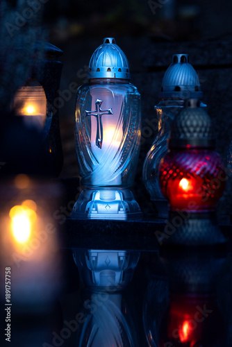 Lit burning candle at night on black stone monument in cemetery. Memory of the deceased. Expression of love