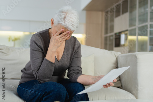 Sad tired ill sick lonely disappointed older senior woman reading bad news at home alone. Unhappy mature grandmother experiencing grief relative death. Stressed elder lady with paper document bill