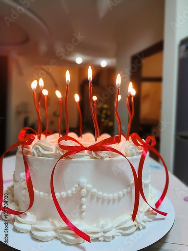 white cake with red bows and candles