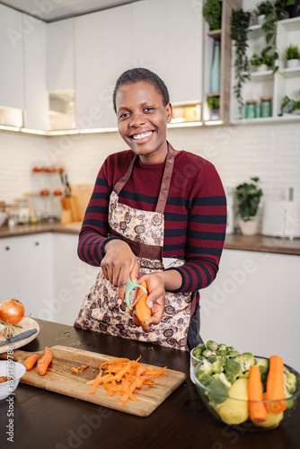 Wallpaper Mural Woman smiling while peeling carrots preparing healthy meal Torontodigital.ca