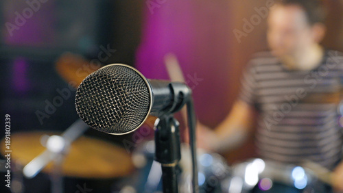 Canvastavla Close-up of a microphone with a blurred drummer in the background