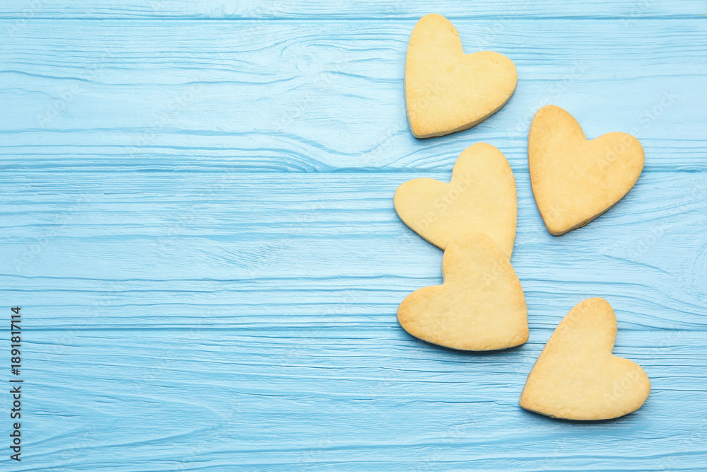 Obraz premium Delicious heart shaped butter cookies on light blue wooden table, flat lay. Space for text