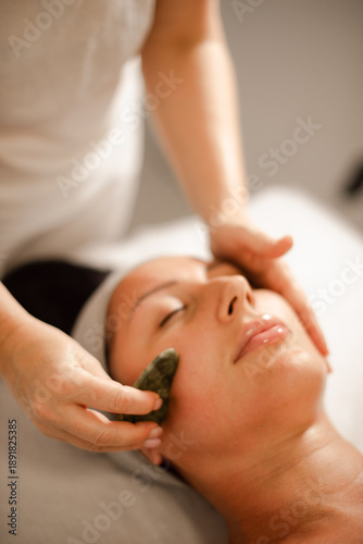 female masseur doing facial massage for client with gouache