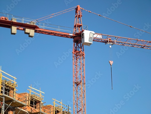 construction crane action, lifting operations underway under clear blue sky at bustling building
