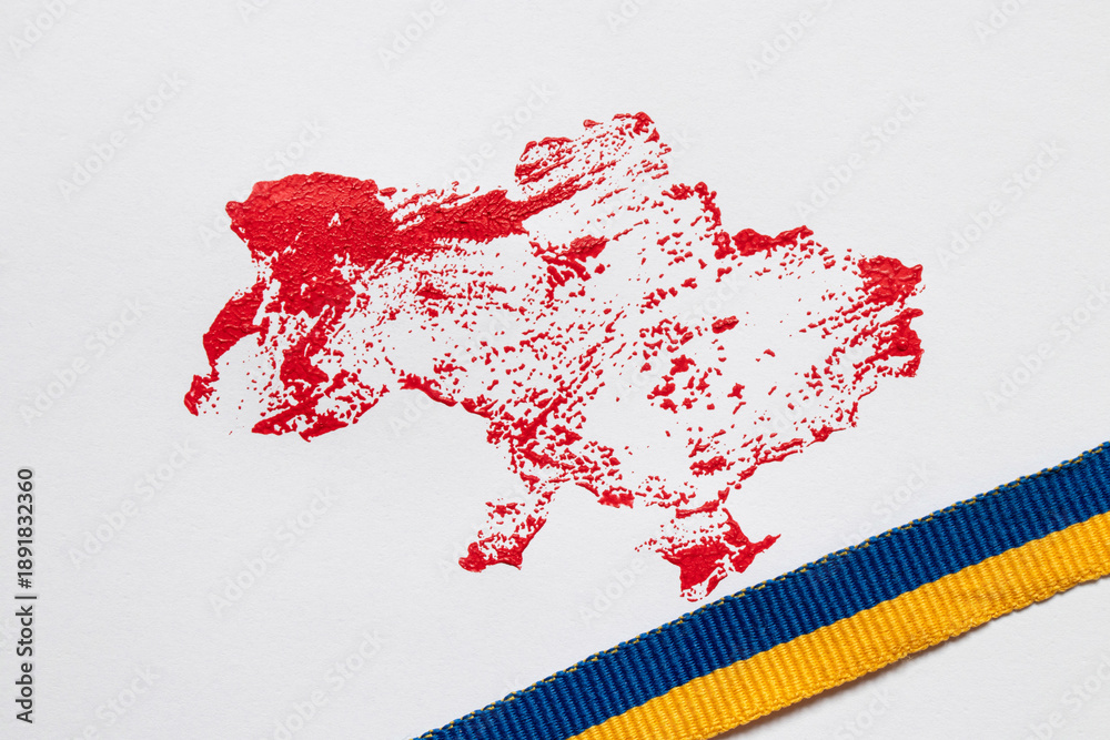 Naklejka premium The outline of the map of Ukraine, drawn in red paint and the ribbon of the Ukrainian flag on a white background