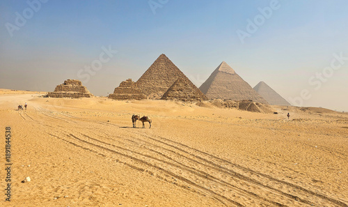 Wide panoramic view of the Great Pyramids of Giza under a clear blue sky, showcasing ancient Egyptian architecture and the vast desert landscape near Cairo, Egypt.