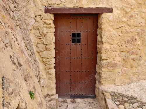 Obraz na plátně Weathered wooden door embedded within stone structure featuring iron studs and s