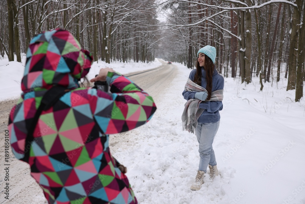 Fototapeta premium Professional photographer taking picture of woman outdoors on winter day