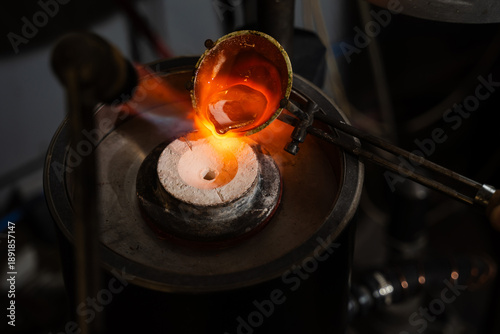 Jeweler pouring molten silver into a preheated mold for jewelry casting.