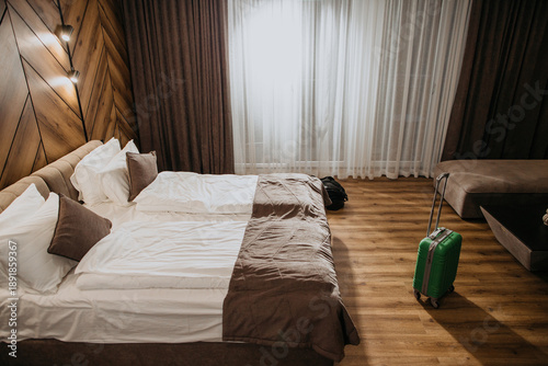 Green suitcase standing in modern hotel room