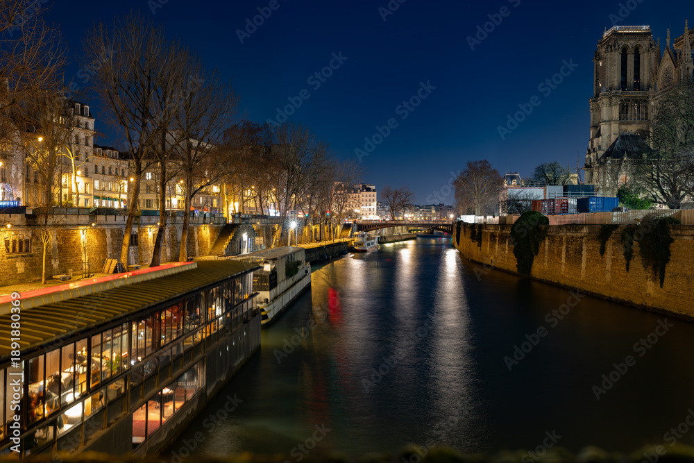 Obraz premium Night view of the Seine River in Paris with illuminated embankments and Notre Dame Cathedral