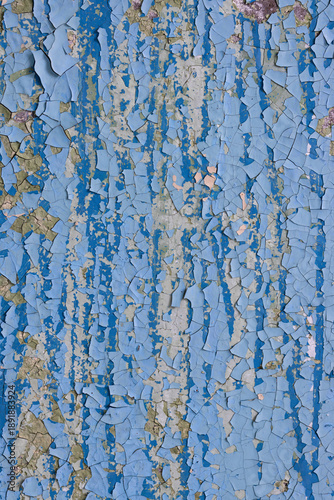 Peeling paint on the wall. Old concrete wall with cracked flaking paint. Weathered rough painted surface with patterns of cracks and peeling. Grunge texture for background and design. High resolution.