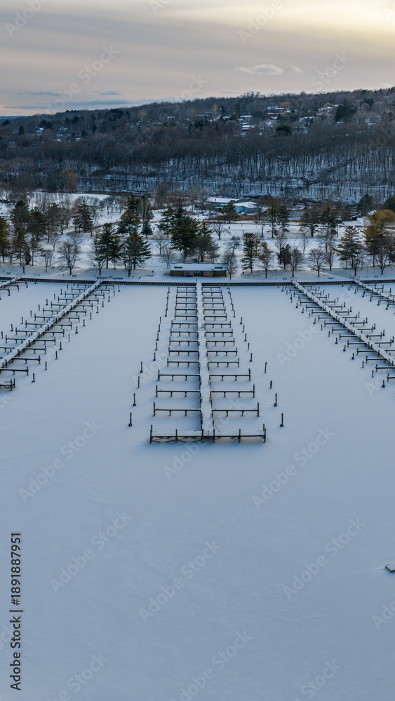 Fototapeta premium Ithaca, NY, USA. 01-24-2026 Vertical winter aerial photo of frozen, snowy marina, docks at Allan H Treman State Marine Park,