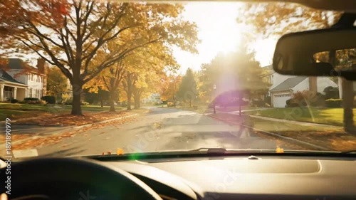 Driving through a picturesque autumn neighborhood with vibrant fall foliage and sunlight streaming through the trees