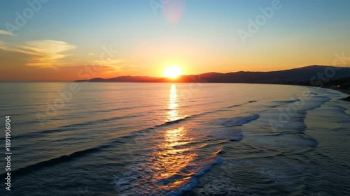 Scenic aerial view of a breathtaking sunset over the calm ocean reflecting the vibrant colors of the sky