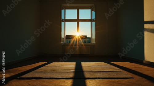 Sunlight streaming through a window into an empty room at sunrise. Golden hour light casting long shadows on a wooden floor. New home and fresh start concept