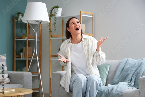 Young woman suffering from noisy neighbours on sofa at home