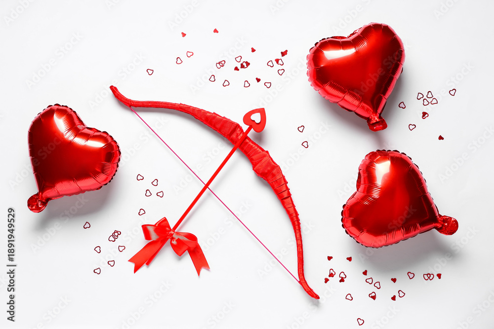 Fototapeta premium Composition with red cupid's bow and heart shaped balloons on light background. Valentine's Day celebration