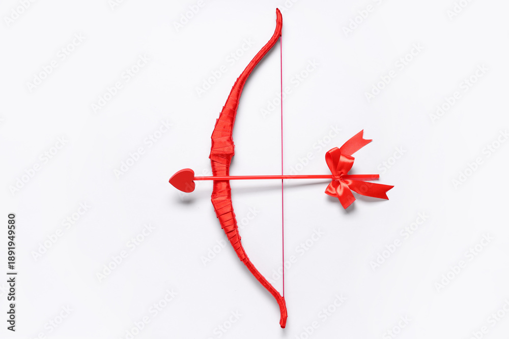 Obraz premium Red cupid's bow with arrow on light background. Valentine's Day celebration