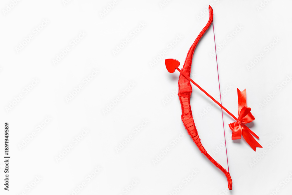 Obraz premium Red cupid's bow with arrow on light background. Valentine's Day celebration