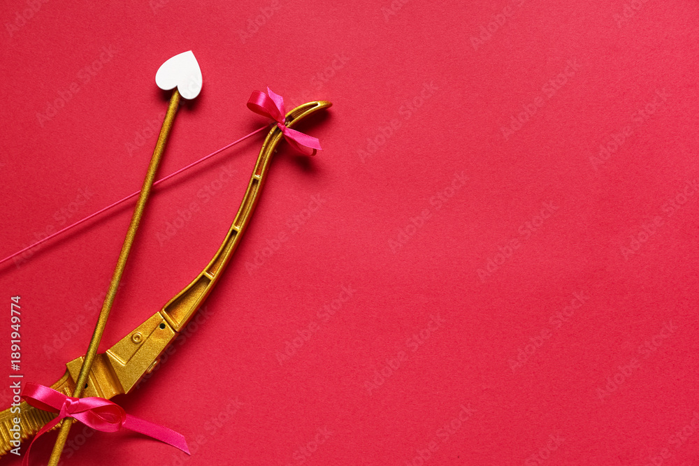 Fototapeta premium Golden cupid's bow with arrow on red background. Valentine's Day celebration