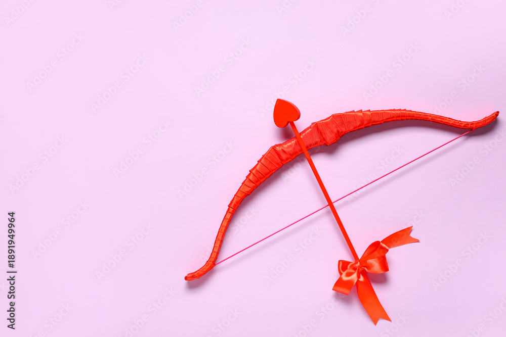 Obraz premium Red cupid's bow on lilac background. Valentine's Day celebration