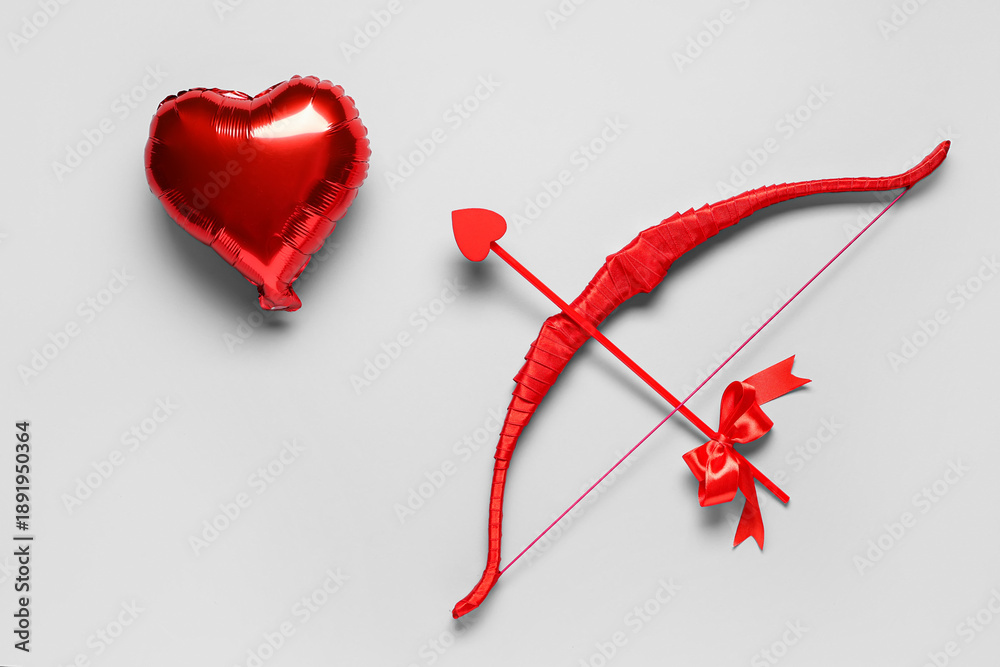 Fototapeta premium Cupid's bow and heart shaped balloon on grey background. Valentine's Day celebration