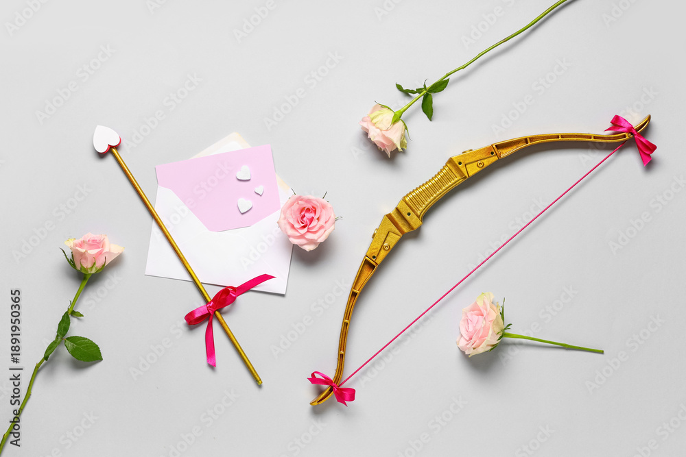 Fototapeta premium Composition with cupid's bow, rose flowers, envelope and card on grey background. Valentine's Day celebration