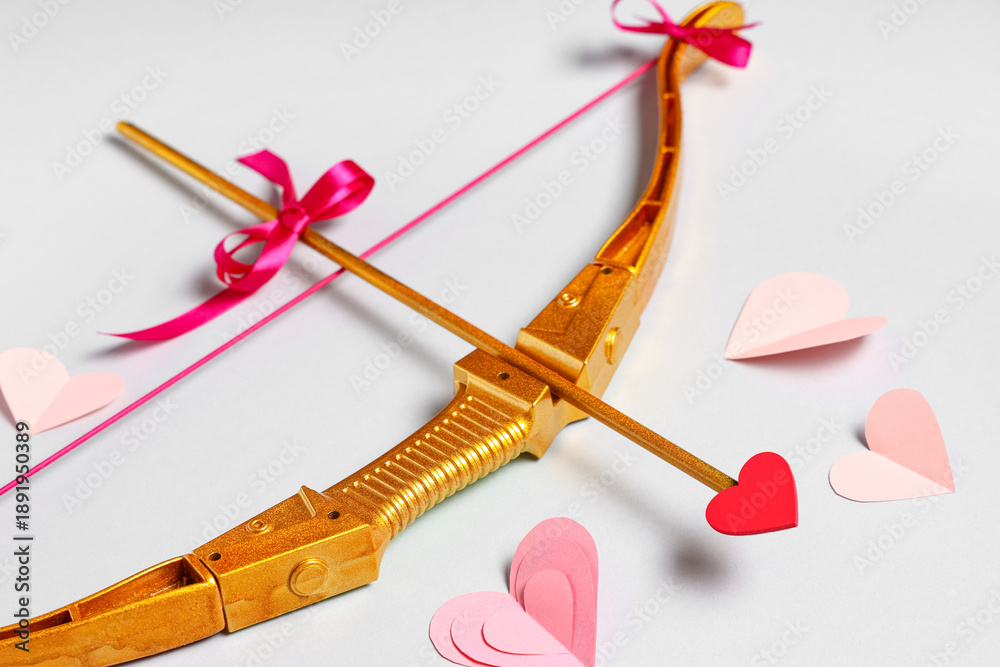 Fototapeta premium Composition with cupid's bow and paper hearts on grey background, closeup. Valentine's Day celebration
