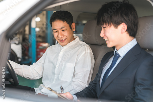 Canvas Print A male customer listening to a salesman's explanation inside a car at a showroom