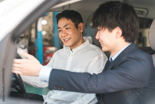 Принти на полотні A male customer listening to a salesman's explanation inside a car at a showroom