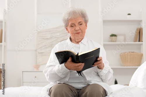 Senior woman on bed reading...